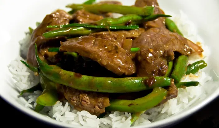 Plat a base de riz, haricots verts et viandes en sauce